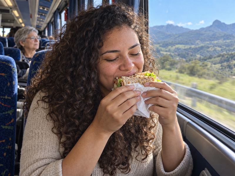 Passageira comendo o sanduíche do kit lanche durante a viagem de ônibus